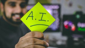 man holding out a sticky note with AI written on it