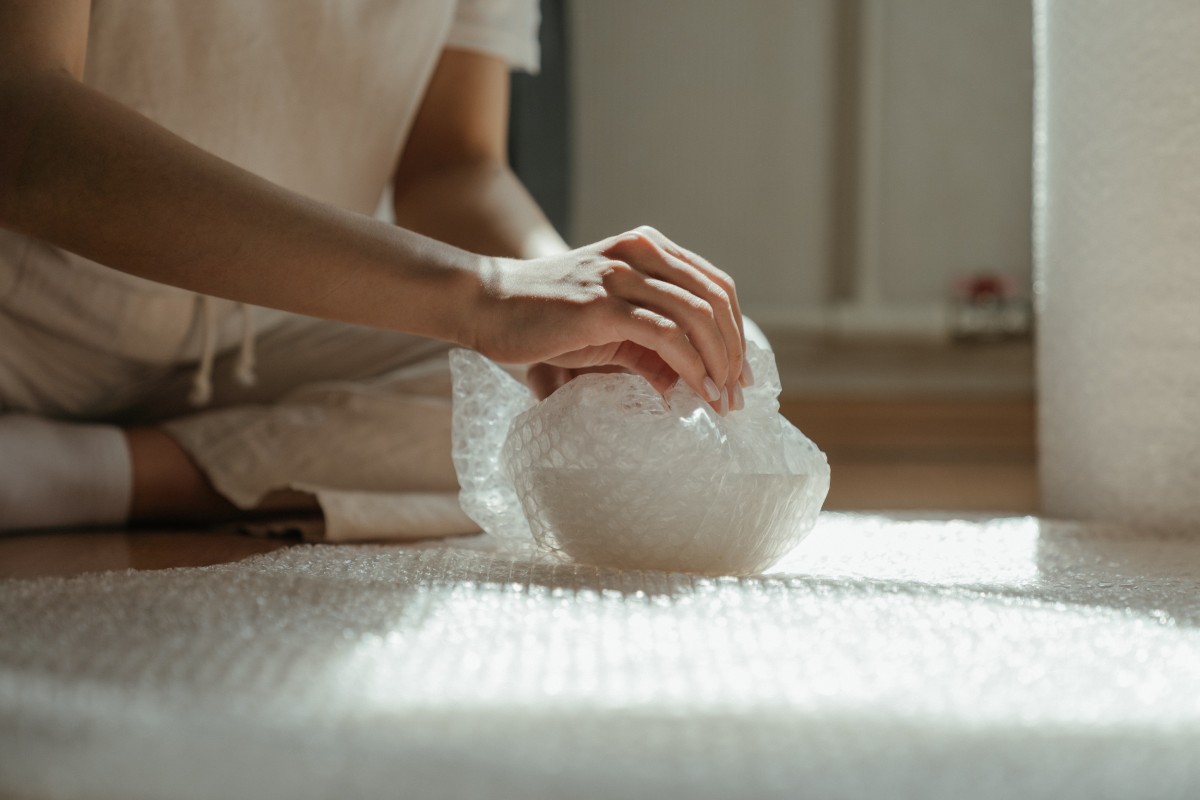 Person wrapping a bowl using a bubble wrap