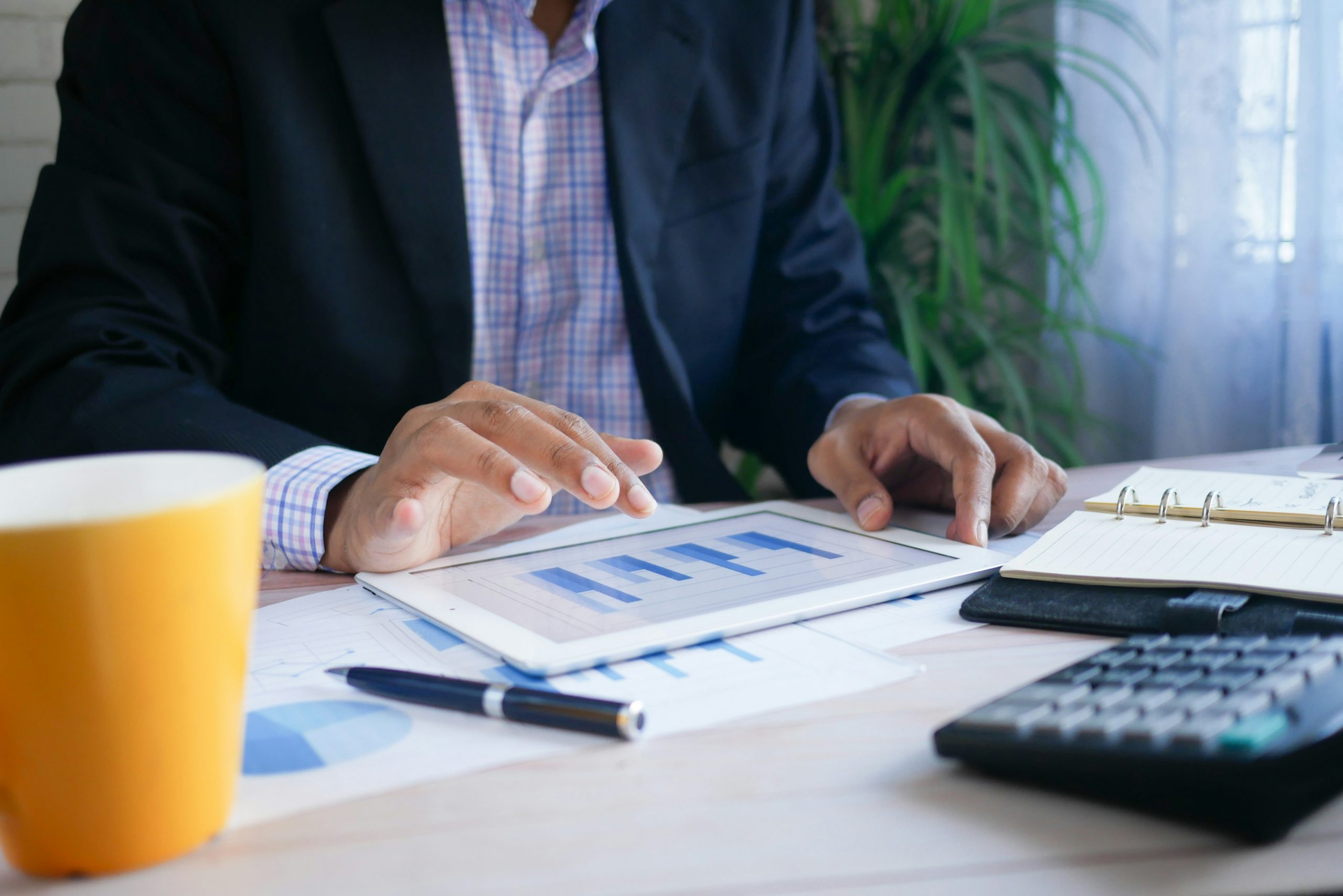 man in a suit interpreting a bar graph, with a calculator on his desk